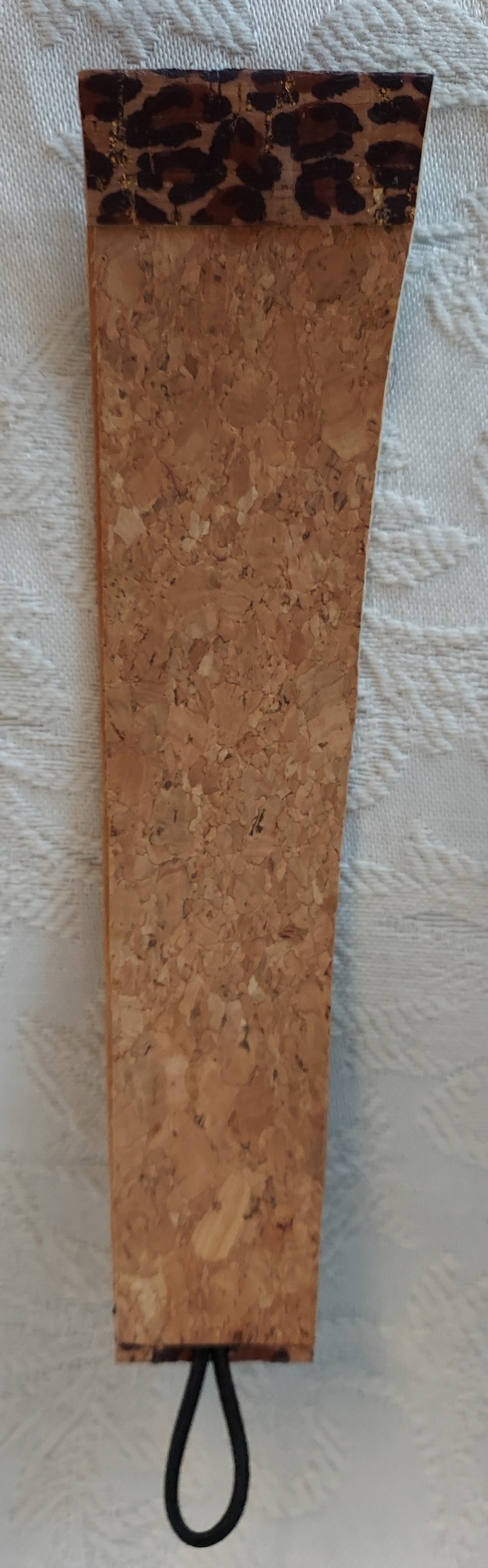 Backside of leopard-themed cork bracelet highlighting natural cork material with a sleek black loop closure.